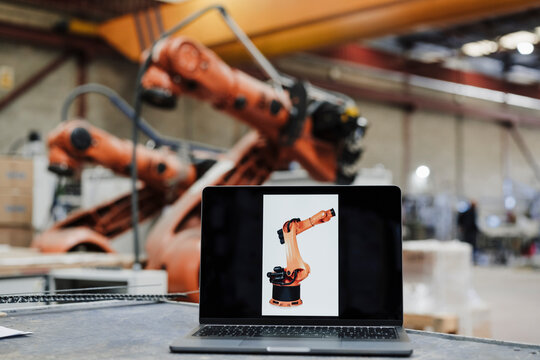Laptop with robotic arm photograph at desk in industry