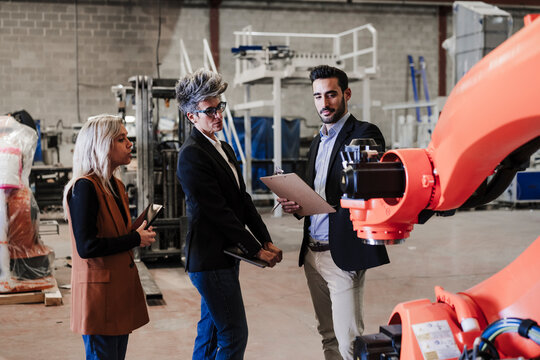 Engineers Discussing Over Robotic Arm In Industry