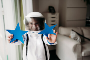 Girl wearing space costume showing blue stars at home