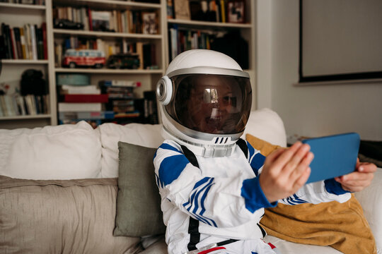 Girl wearing space costume having video call on mobile phone at home