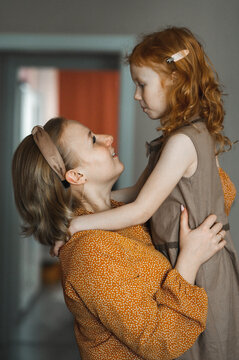 Happy Mother Playing And Embracing Daughter At Home