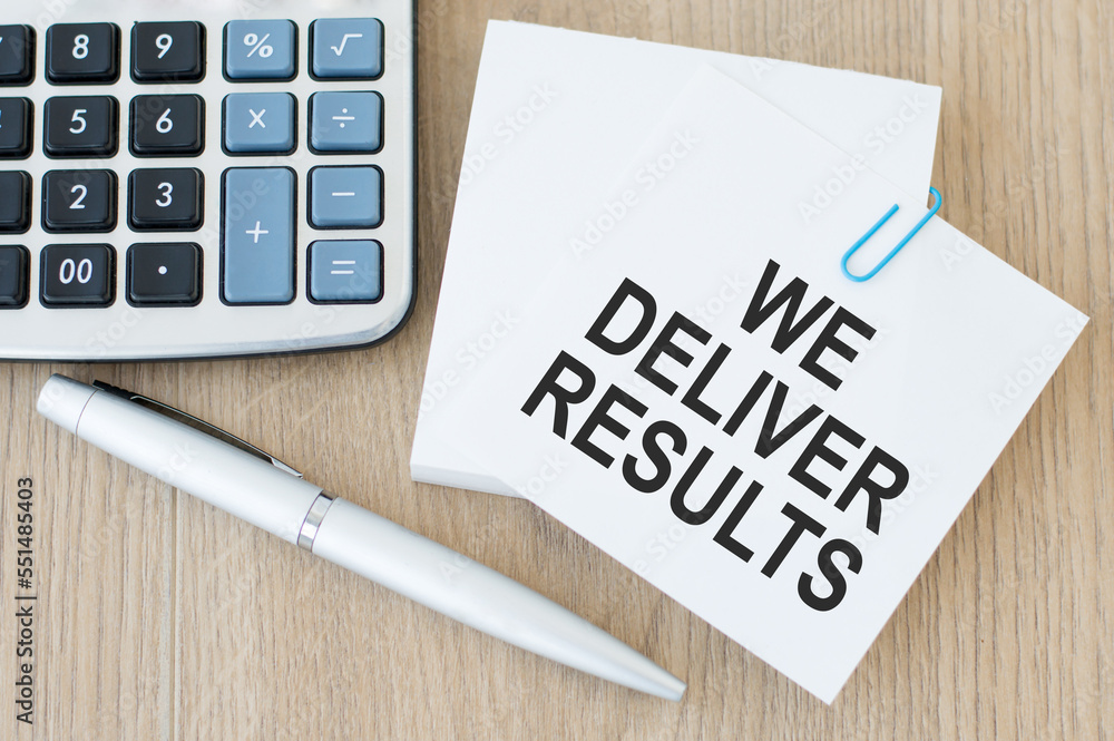 Poster a white business card with we deliver results text stands on a desk against the background of an ope