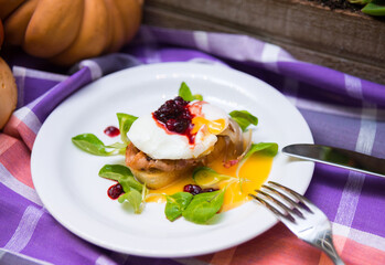 Poached egg on bruschetta with bacon and cranberry jam, corn salad