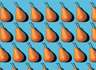 Colorful pear pattern. Yellow and orange Bera pears on a blue background. Ripe juicy fruits top view. Food background. Creative concept.