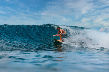 Shirtless male surfer on a wave at sunny day