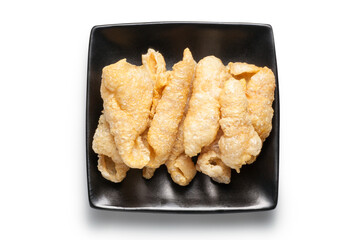 fried pork rinds on a black plate isolated on white background