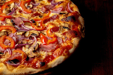 Italian pizza with vegetables, meat and cheese on a wooden board. Italian cuisine. Close-up