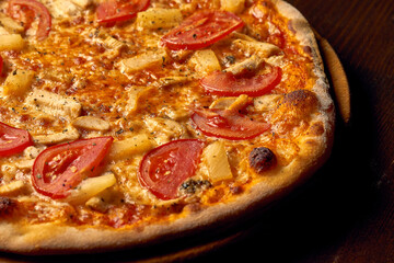 Italian Hawaiian pizza with chicken and pineapple on a wooden board. Italian cuisine. Close-up