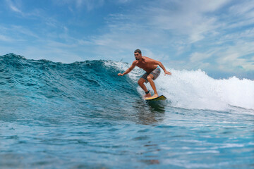 Shirtless male surfer on a wave at sunny day - 551487299