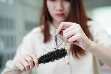 Asian woman have problem with long hair loss attach to comb brush.