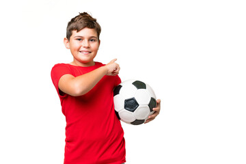 Little caucasian kid over isolated chroma key background with soccer ball and pointing to the...
