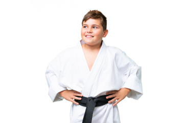 Little caucasian kid doing karate over isolated chroma key background posing with arms at hip and smiling