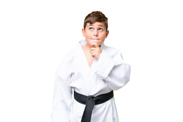 Little caucasian kid doing karate over isolated chroma key background having doubts and thinking