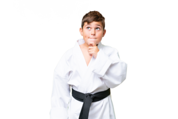 Little caucasian kid doing karate over isolated chroma key background having doubts and thinking