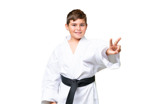 Little caucasian kid doing karate over isolated chroma key background smiling and showing victory sign