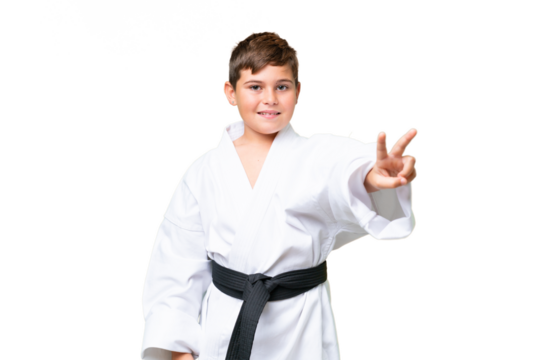 Little caucasian kid doing karate over isolated chroma key background smiling and showing victory sign