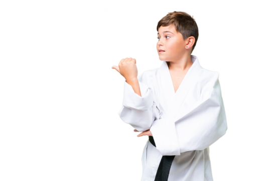 Little caucasian kid doing karate over isolated chroma key background pointing to the side to present a product