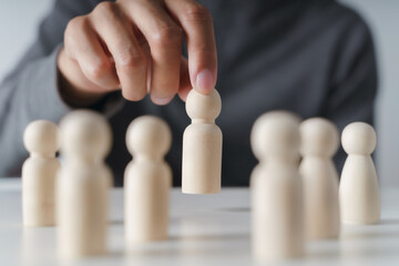 Man hand chooses wooden peg doll. leadership and business team creative thinking and human...