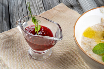 Porridge with pine nuts, decorated with mint leaves. There is jam next to it.
