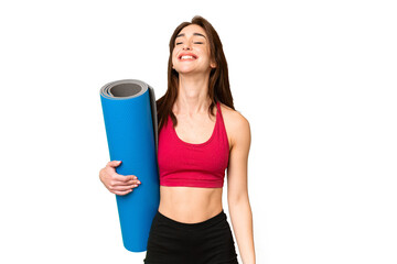 Young sport caucasian woman going to yoga classes while holding a mat over isolated chroma key background laughing