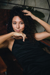 Fototapeta premium Portrait of a smiling curly woman sitting in a chair
