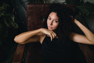 Portrait of a smiling curly woman sitting in a chair