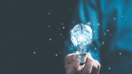 Fototapeta Businessman hand holding lightbulb with glowing virtual brain and  connection line to creative smart thinking for inspiration and innovation with network concept. obraz