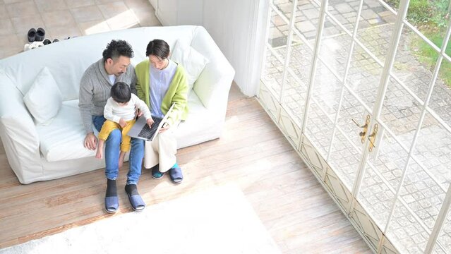 リビングにて家族でパソコンを覗いているイメージの動画　広角 俯瞰