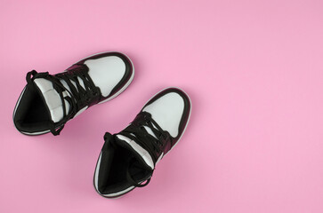 Stylish new sneakers for advertising a shoe store. Black and white sneakers on a pink background, top view.