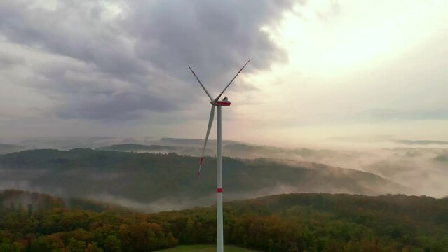 drone shot of a wind turbine. In the background is forrest with a lot of fg