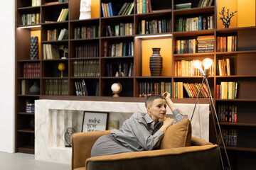 stylish woman resting in a chair on the background of the interior with a home library