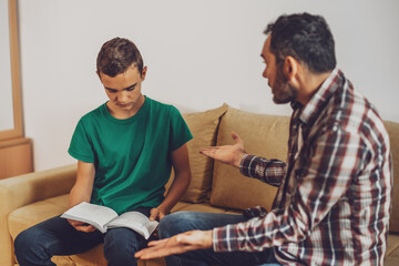 Father is helping his son with learning. They are doing homework together.