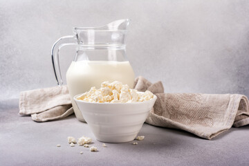Healthy cottage cheese in white bowl with glass milk jug