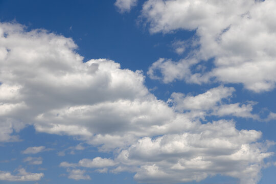 Summer blue sky of various shades and white fluffy light cumulus clouds floating in height