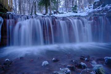 A small waterfall shot with a long exposure in a winter landscape. Very late evening, dusk