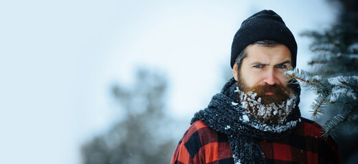 Close up portrait of serious bearded man in snow. Angry winter man with beard in snow on serious...