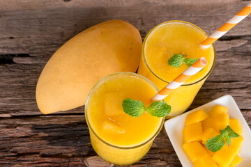 Naklejka na ściany i meble Mango juice fruit smoothies yogurt drink yellow healthy delicious taste in a glass slush for weight loss on wooden background.