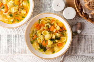 Minestrone soup with pasta orecchiette and seasonal vegetables. on a light table, top view. Delicious vegetarian italian food concept. Flat lay.