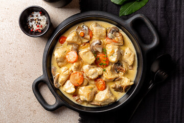 Top view of Blanquette de poulet, is a French chicken stew with carrots, mushrooms, onion. Simmered in a white stock and served in a sauce enriched with cream, herbs.