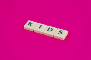 Leisure activity for kids concept, kids text on white blocks, word game idea, isolated on pink background, playing board game, educational games for children