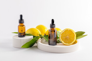 two cosmetic bottles of amber glass with a dropper with lemon serum or facial skin care oil stand...