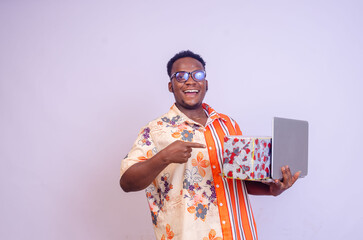 excited african man holding a package and laptop pointing to the side