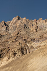 The rocky mountains of the Himalayas against a dark blue sky.