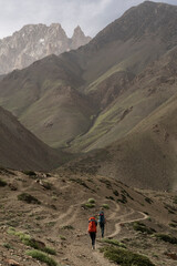 A pair of climbers walking in the mountains with backpacks. Small Himalayas 