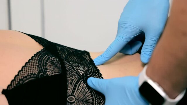 Orthopedic specialist conducts a close-up examination of a woman's back. Diagnosis of protrusion by a doctor