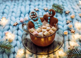 Concept of couples spa Christmas holiday. Couple woman and a man made out of an gingerbread that soak in cup of hot chocolate with marshmallows, cozy winter setting.