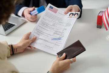 Close up of woman getting US visa in immigration office and holding approved forms - obrazy, fototapety, plakaty