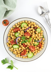 Chickpea salad with tomatoes, cucumber, onion and greens on a white background. Top view. Oriental and Mediterranean cuisine.