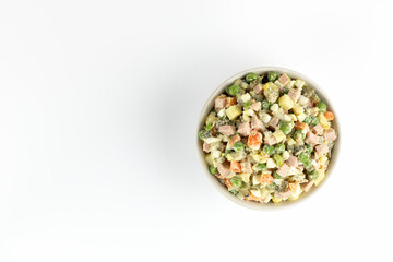 Traditional Russian Olivier salad. Russian New Year or Christmas salad of boiled vegetables, sausage, eggs and mayonnaise on a white background. Top view, copy space.