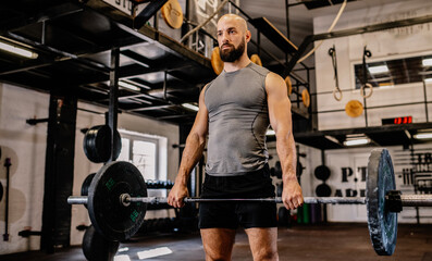 A portrait of a male weightlifter in sportswear. He does barbell fitness workout in the modern gym....